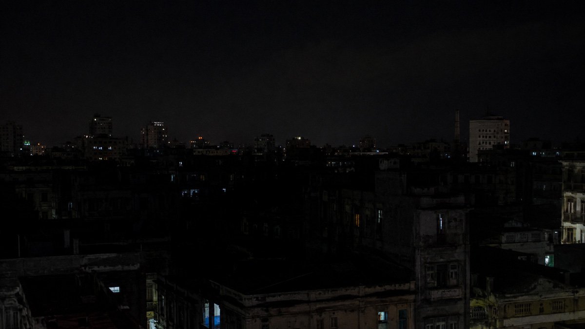 Horizonte urbano nocturno con apagón, edificios en penumbra y pocas ventanas iluminadas Horizonte urbano nocturno con apagón, edificios en penumbra y pocas ventanas iluminadas