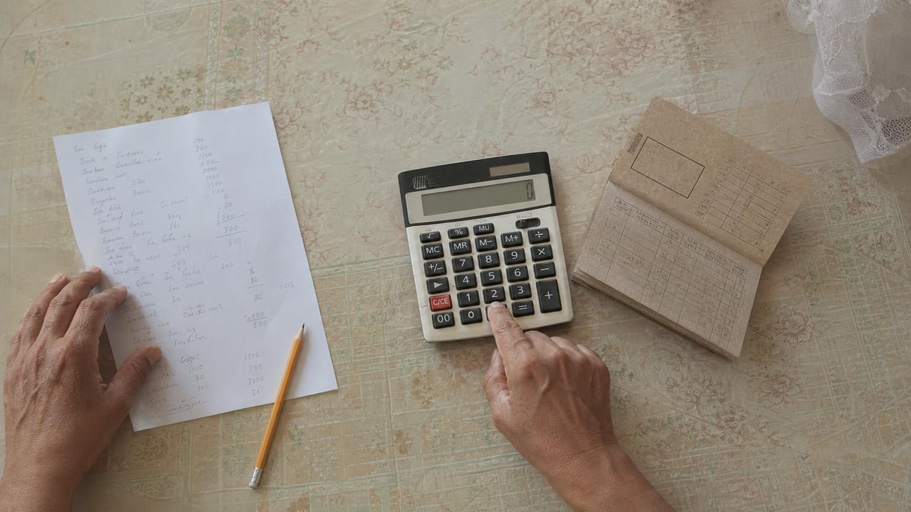 Calculadora y libreta de abastecimiento cubana sobre una mesa para calcular el presupuesto familiar mensual en Cuba