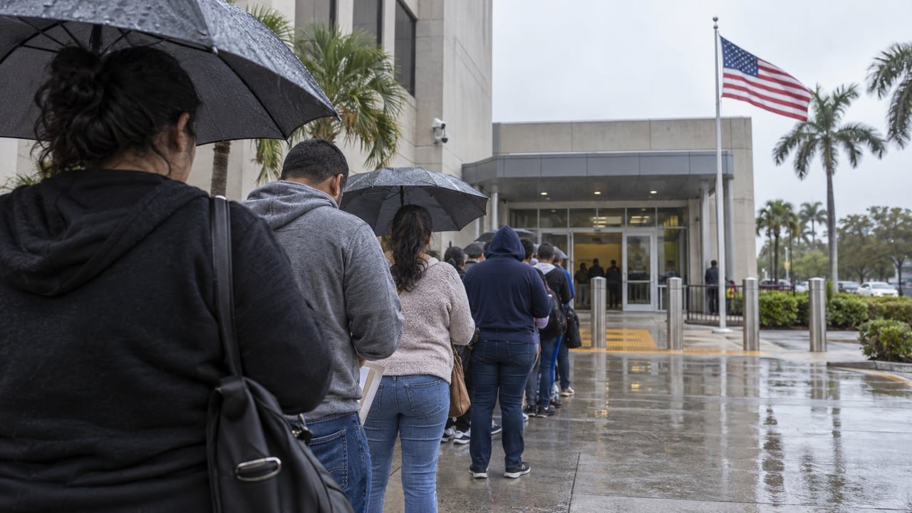 Fila de personas esperando bajo la lluvia frente a un edificio federal de inmigración en Miami-Dade durante la ofensiva migratoria de ICE