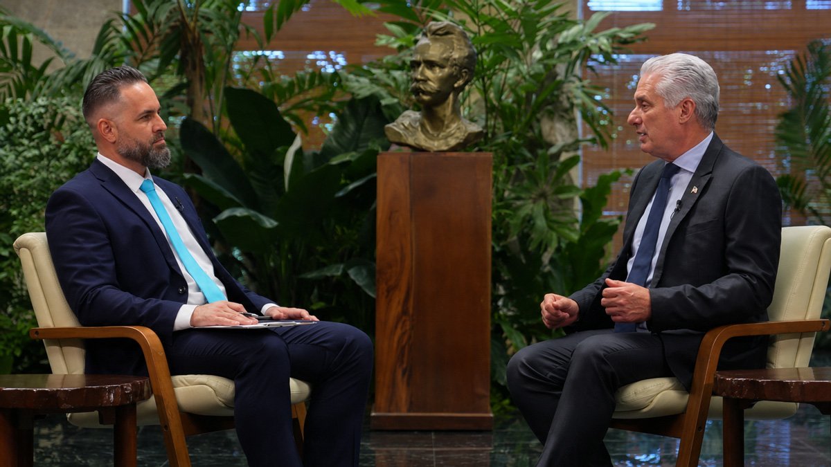 Escudo de Cuba junto a un informe de reforma económica sobre un escritorio, en referencia al contraste entre el modelo de Díaz-Canel y el plan de los economistas